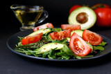 Green tossed salad with leafy vegetables, arugula, baby spinach, avocado,  tomatoes and seeds. Ketogenic low-carb diet food