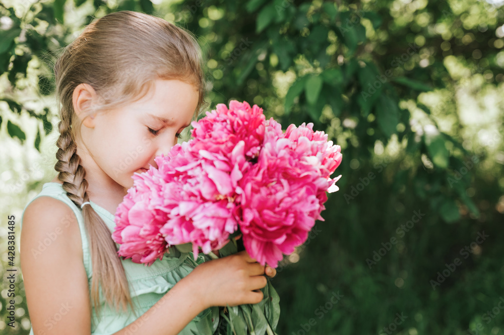 portrait of a happy cute little caucasian seven year old kid girl, holds in hands and smell and enjoying a bouquet of pink peony flowers in full bloom on the background of nature portrait of a happy cute little caucasian seven year old kid girl, holds in hands and smell and enjoying a bouquet of pink peony flowers in full bloom on the background of nature