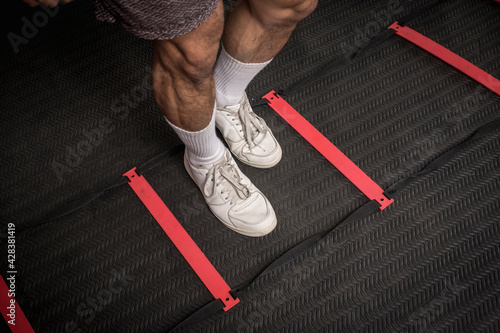 Closeup of footwork on an agility ladder. Feet inside the square. Fitness, cardio and intense sports training concept. photo