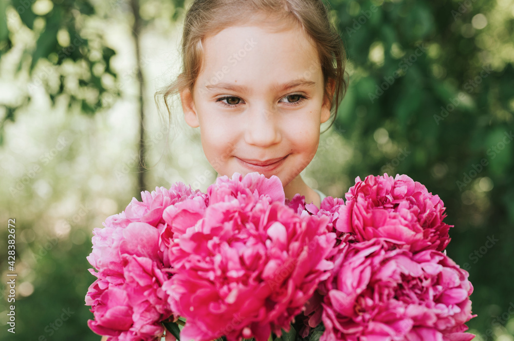 portrait of a happy cute little caucasian seven year old kid girl, holds in hands a bouquet of pink peony flowers in full bloom on the green background of nature portrait of a happy cute little caucasian seven year old kid girl, holds in hands a bouquet of pink peony flowers in full bloom on the green background of nature