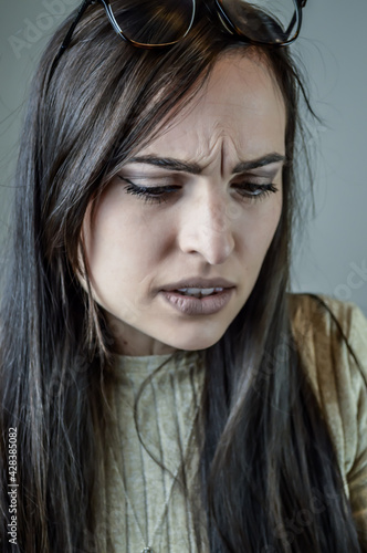 Portrait of a beautiful young woman with long brown hair with a frowning look because she is bothered by something