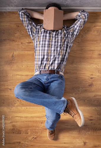 Man relaxing on floor thinking idea solitions. Man student lying studying and book on face photo