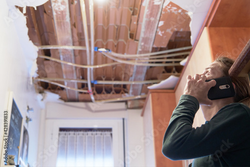 Фотография Woman talking to homeowner's insurer while inspecting kitchen ceiling