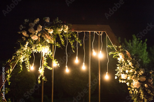 The close up of wedding ceremony with arch in rustic style with fresh flowers and macrame