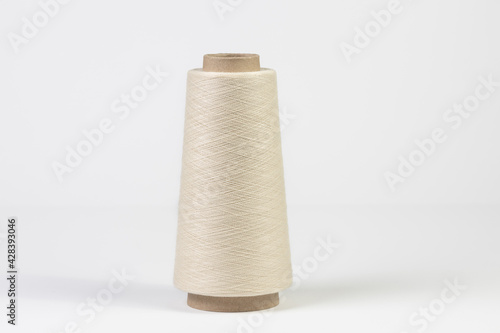 Large spool of white woolen thread, close-up with shallow depth of field. Isolated on white background