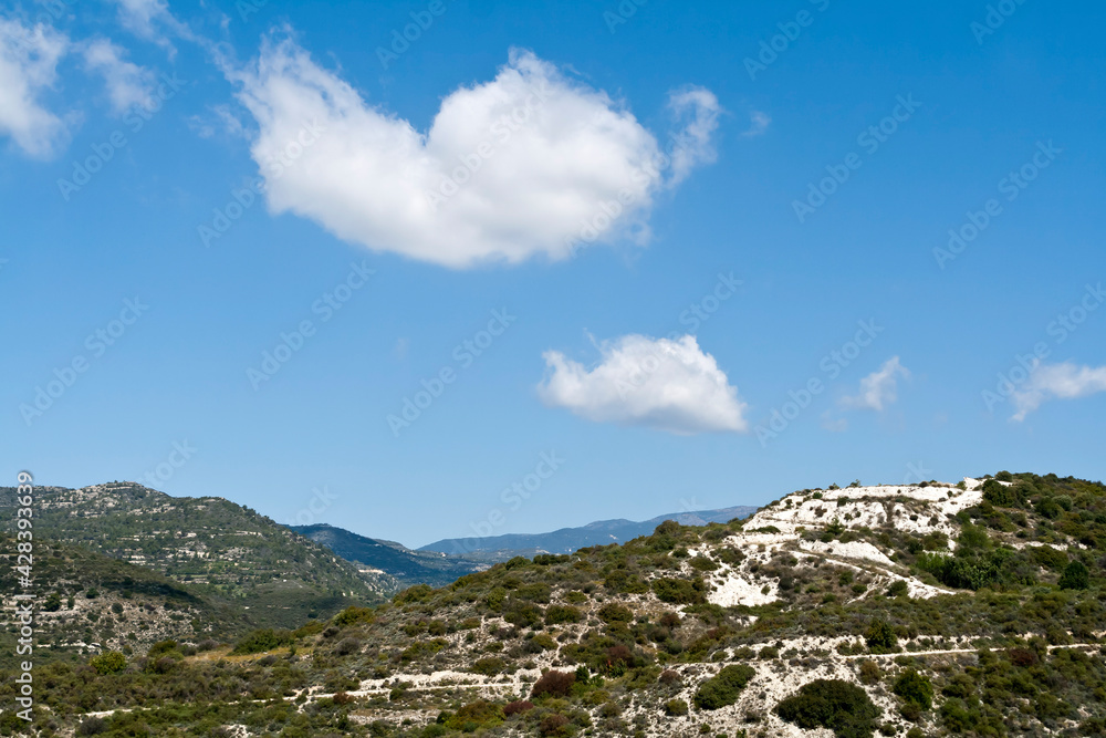 Blue sky with white clouds above green mountains  