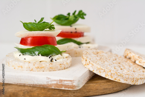Rice cake sandwich with cheese cream, mozzarella, tomato, basil and spices. A healthy dietary snack