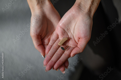 Woman hands holding hearing aid