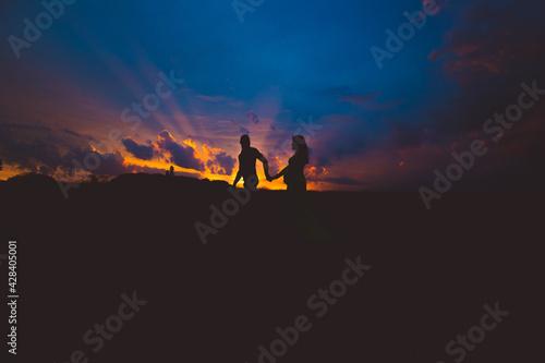 pregnant woman and her husband walking in the sunset