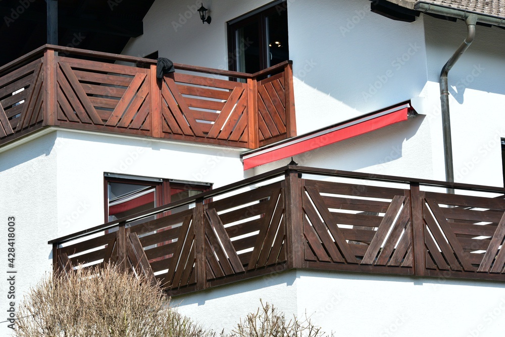 Moderner Balkon mit lasiertem Holzgeländer an einer Wohnhausfront Stock