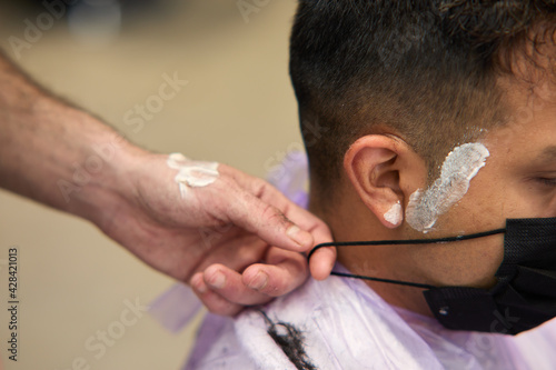 hairdresser with mask shaving with razor