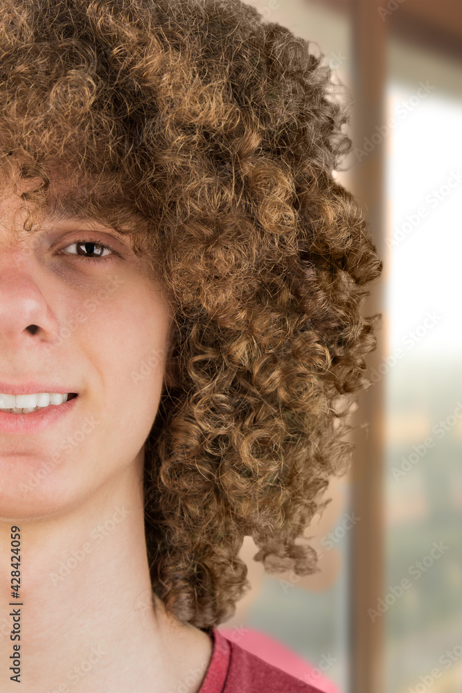 split in half cropped portrait of a young curly European man with long curly hair and a dreamy smile close-up against the window. very lush male hair. curling hair men's. a lock of passion split in half cropped portrait of a young curly European man with long curly hair and a dreamy smile close-up against the window. very lush male hair. curling hair men's. a lock of passion