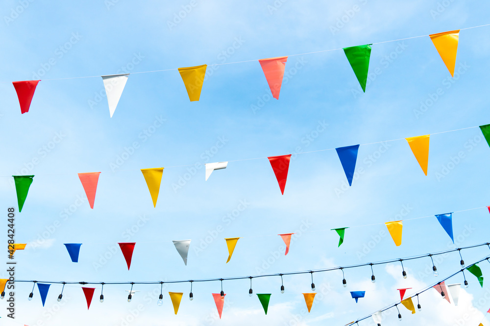 Colorful triangular flags hanging on a string Under the bright blue sky. Colorful triangular flags hanging on a string Under the bright blue sky.