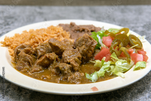Bild auf Leinwand Authentic Mexican food plate of chili verde pork smothered in green sauce served with refried beans and rice