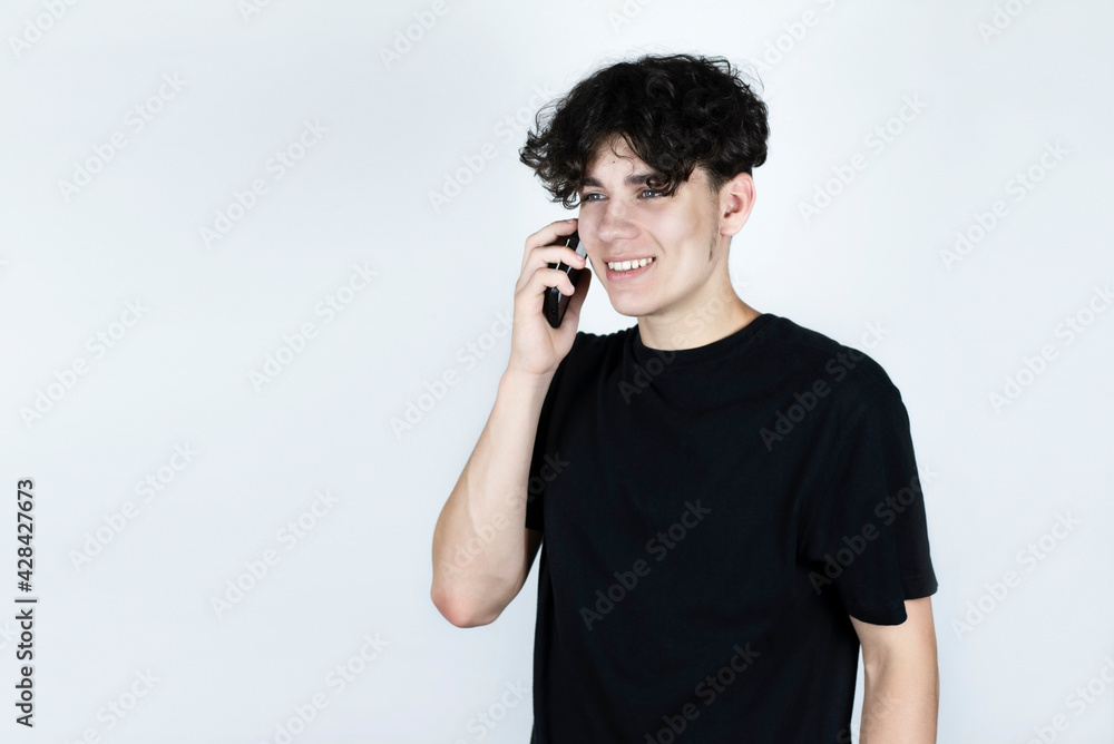 The teenage boy talks on the phone and smiles, he has not talked to a friend for a long time, and the guy is always in a good mood after talking to a friend The teenage boy talks on the phone and smiles, he has not talked to a friend for a long time, and the guy is always in a good mood after talking to a friend
