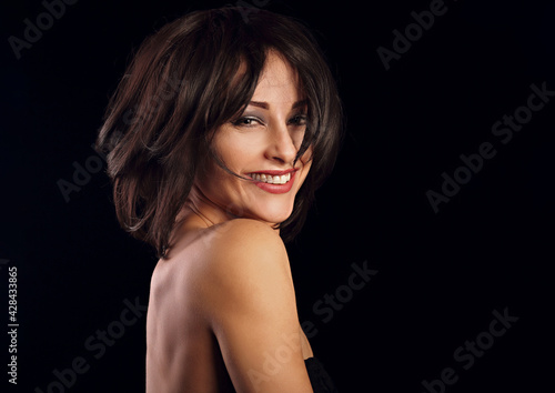 Happy laughing bright makeup woman shaking her black short hair on black background. Closeup portrait