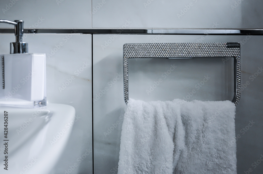 Detailaufnahme eines Badezimmers. Angefertigter strassbesetzter Handtuchhalter, Handtuchring mit  weißem Handtuch - obrazy, fototapety, plakaty 