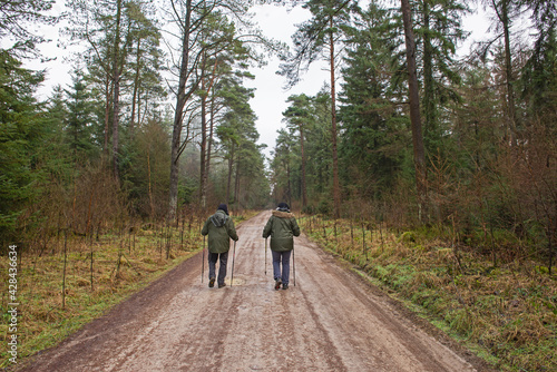 Couple walking on footpath through rural countryside woodland