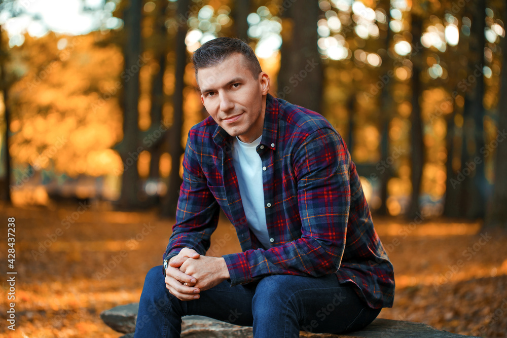 Handsome smiling man sitting on a bench in the autumn park Handsome smiling man sitting on a bench in the autumn park