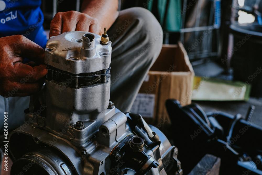 Fototapeta premium Mechanic is working on a two-stroke engine cylinder head.
