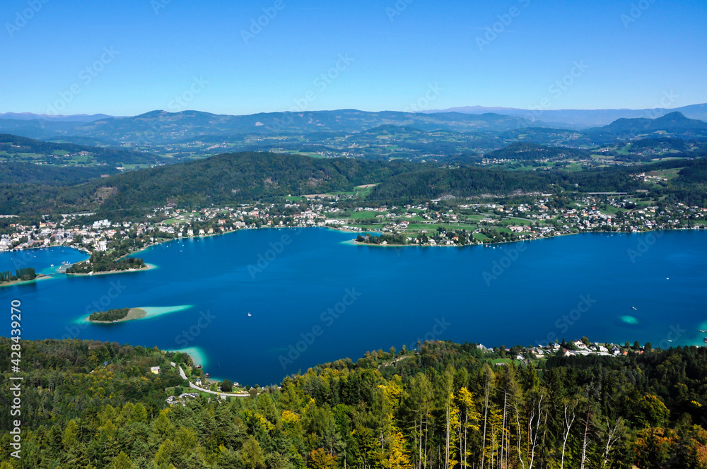 Blick aus gr0ßerer Höhe auf einen wunderschönen See, umrandet von Bergen, an einem wolkenlosen Sommertag.