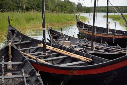 Wooden sailing boats moored to a pier. Birka, Björkö island, lake Mälaren, Sweden. Atmospheric landscape. Travel destinations, landmarks, sightseeing, history, historical reenactment, viking age photo