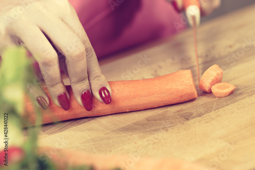 Woman cutting carrot on kitchen board