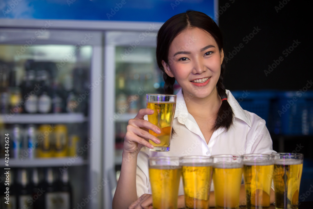 Beautiful Asian woman holding a glass of beer close up on background inside bar. Beautiful Asian woman holding a glass of beer close up on background inside bar.