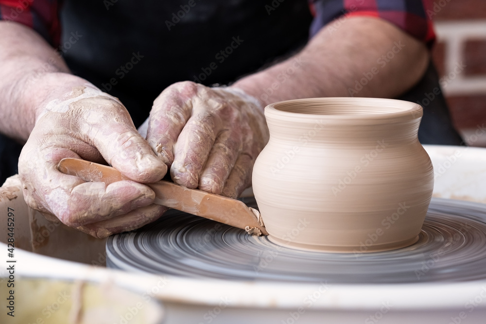 Potter wheel and hands of craftsman making a jug