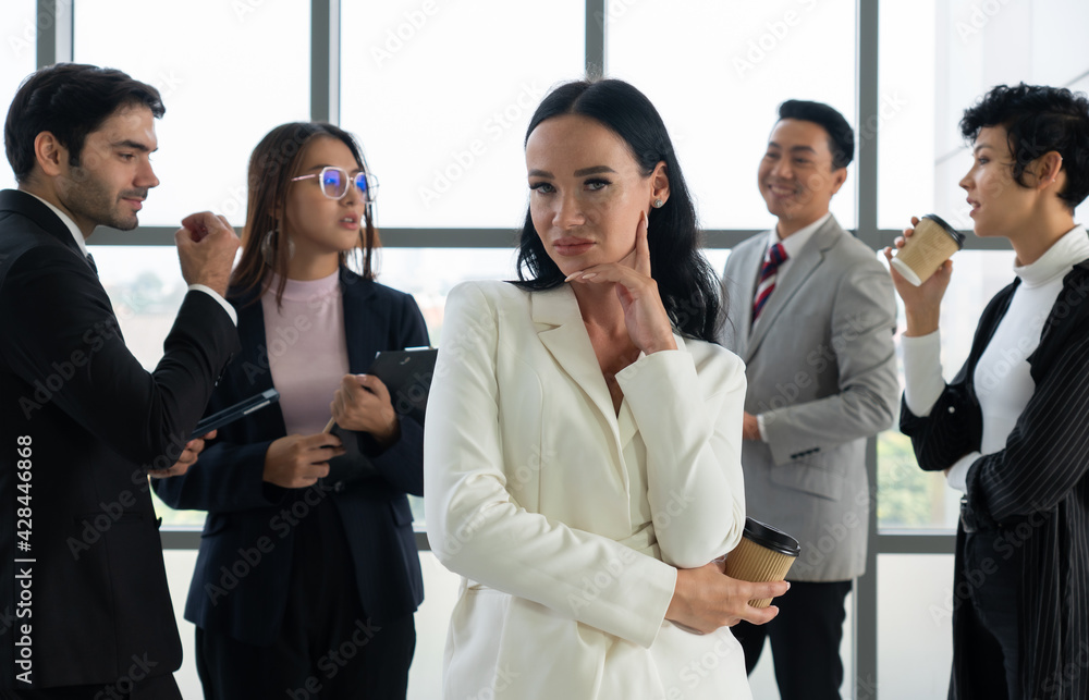 portrait of young caucasian confident businesswoman with smiling face stnading in office with background of multiethnic colleagues. diversity in business concept