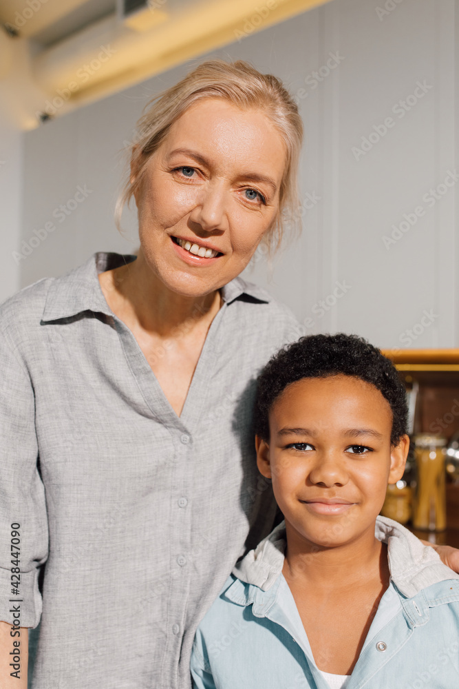 Woman standing at the kitchen with her multiracial son and embracing Woman standing at the kitchen with her multiracial son and embracing