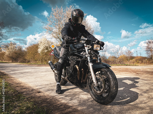 motorcyclist dressed in black sits on his black motorcycle