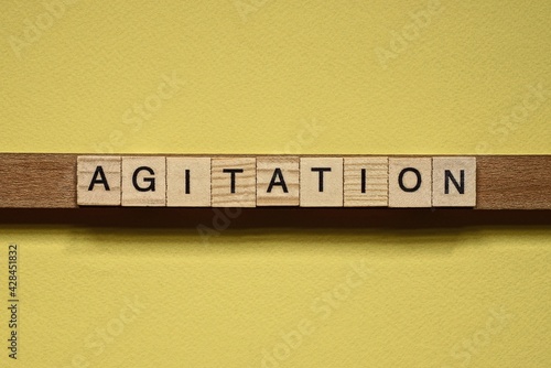 word agitation made from wooden letters lies on a yellow table photo