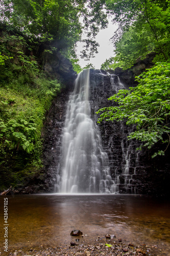 Large cascading waterfall tumbling into a peaceful pool. Falling foss waterfall, Yorkshire Dales 