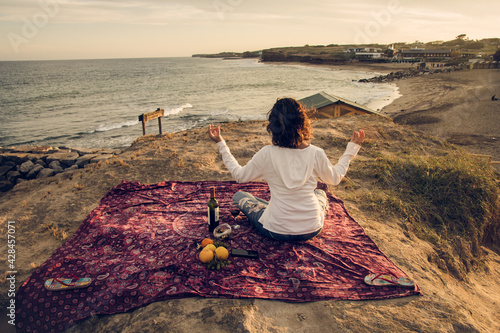 Mujer hace yoga en la playa después del pic- nic photo