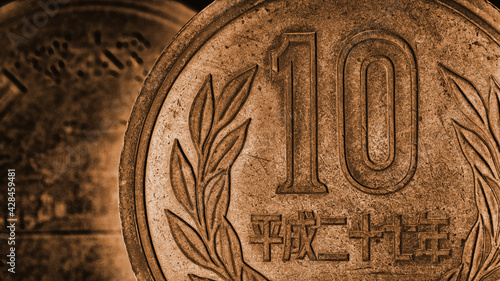 Translation: Japan 2015. Japanese coin of 10 yen close-up. Dark brown dramatic website background. Wallpaper or backdrop about money, economy, finance, taxes and financial management. Macro