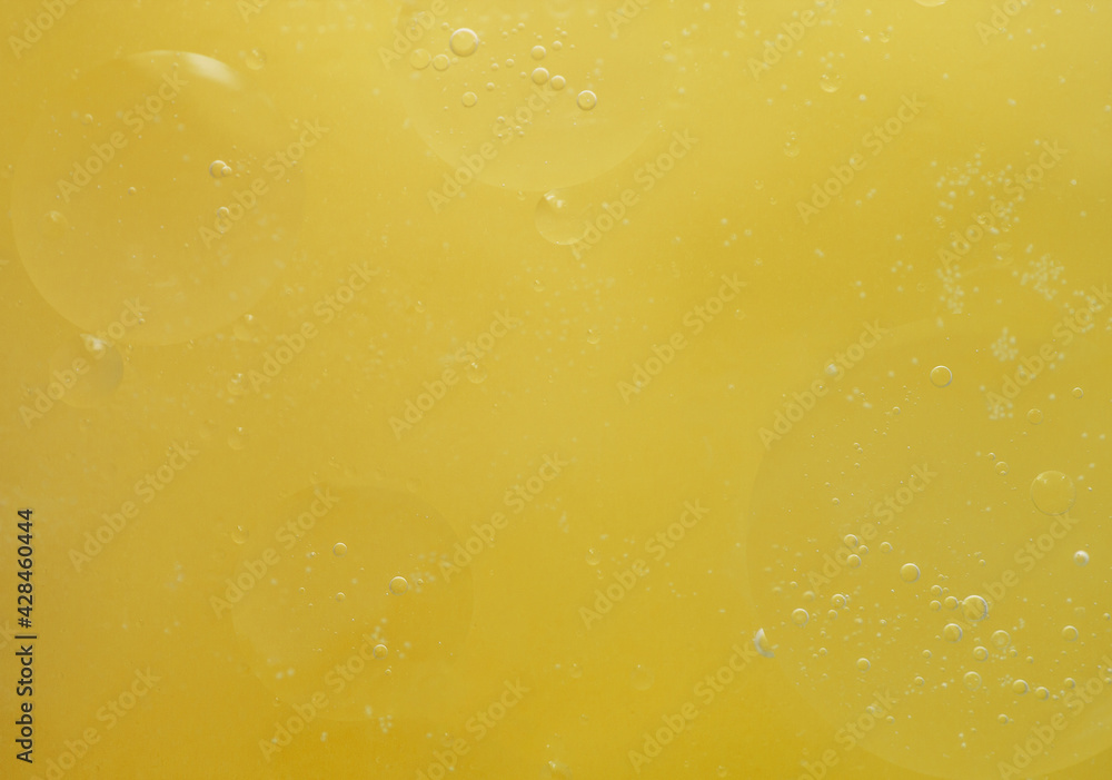 Drops of oil in water on a yellow background