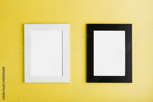 Two frames White and black photo frame on yellow background with free space.