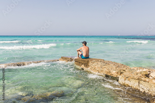 Man sitting on a rock enjoying the view of the sea and the horizon.
