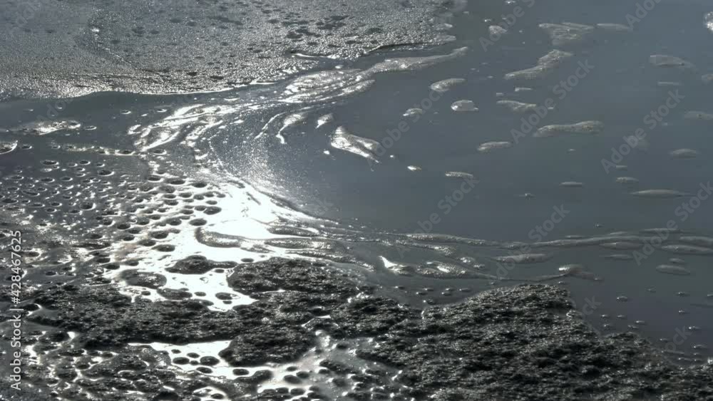 Dirty foam forming on water over melting ice Dirty foam forming on water over melting ice