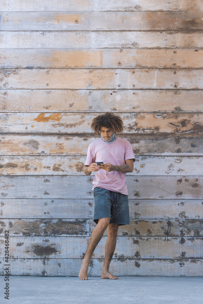 Young afro man uses his smart phone on a Wooden background Young afro man uses his smart phone on a Wooden background
