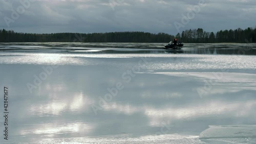 Snowmobile driving over wet surface of frozen lake photo