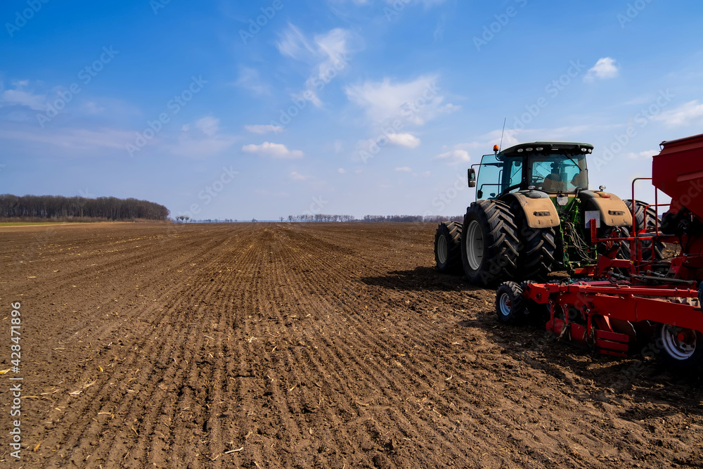 Fototapeta premium tractor with seeder in the field in early spring