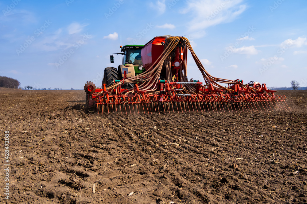 Fototapeta premium tractor with seeder in the field in early spring