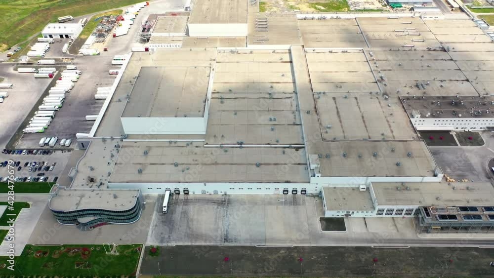 Roofs of the industrial plant. Many buildings constructed together and car parking places of a large modern factory. Top view. Roofs of the industrial plant. Many buildings constructed together and car parking places of a large modern factory. Top view.