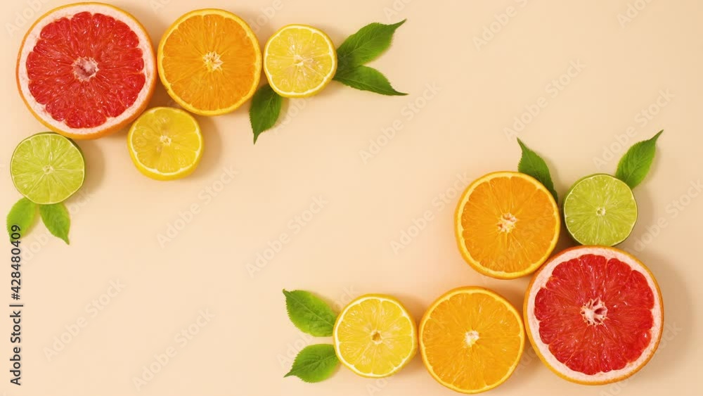 Creative citrus fruits frame with green leaves on sandy background. Stop motion flat lay Creative citrus fruits frame with green leaves on sandy background. Stop motion flat lay
