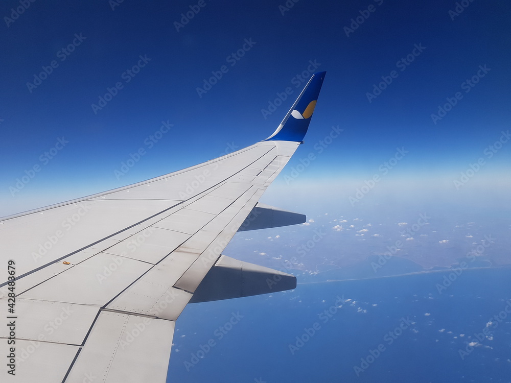 Aircraft Wing outside plane window on blue sky background, closeup Aircraft Wing outside plane window on blue sky background, closeup