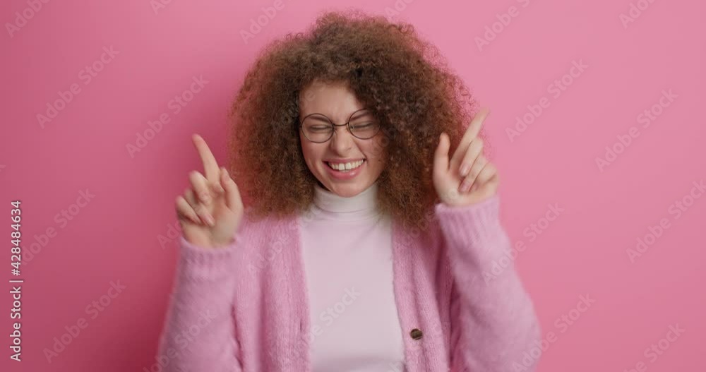 Carefree cheerful European woman dances carefree keeps palms raised feels glad dressed casually isolated over pink background laughs joyfully has fun. People emotions youth freedom happiness concept Carefree cheerful European woman dances carefree keeps palms raised feels glad dressed casually isolated over pink background laughs joyfully has fun. People emotions youth freedom happiness concept