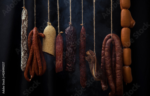 Smoked ham, bacon, pork neck and sausages in a smokehouse.
