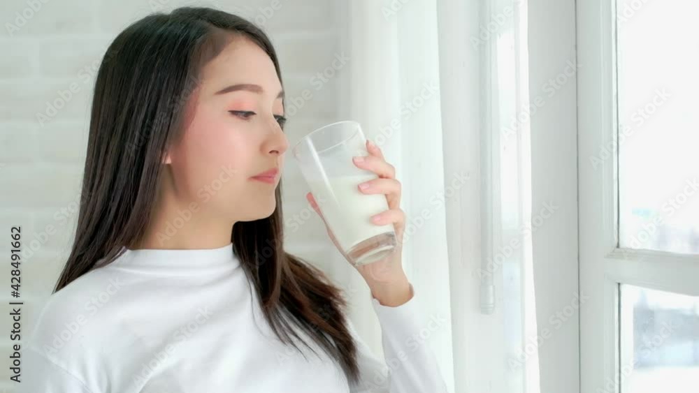 Attractive Asian woman drinking milk and smiling at home close up face.healthy life style. Attractive Asian woman drinking milk and smiling at home close up face.healthy life style.